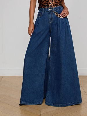 A person wears the L'AGENCE Chayse Wide-Leg Jean in non-stretch denim with a statement chain at the waist and a sleeveless leopard print top, standing on a wooden floor against a plain white wall.