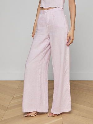A person stands on a wooden floor wearing the Amara Linen Wide-Leg Pant in light pink with a matching sleeveless crop top, arms relaxed at their sides.