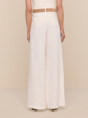 A person is seen from the back wearing the Amara Linen Wide-Leg Pant in cream, featuring a high rise, wide legs, two rear patch pockets, and a tan waistband against a neutral beige background.