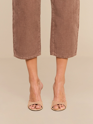 Wearing the Mallis Corduroy Bow-Leg Pant in a cropped, high-rise brown wide-leg silhouette paired with beige open-toe heeled sandals, this look makes a stylish addition to any casual wardrobe.