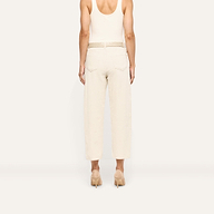 Back view of a person wearing Mallis Corduroy Bow-Leg pants in beige, featuring a high-rise, relaxed wide-leg silhouette and a woven belt, styled with a tank top and heeled pumps.