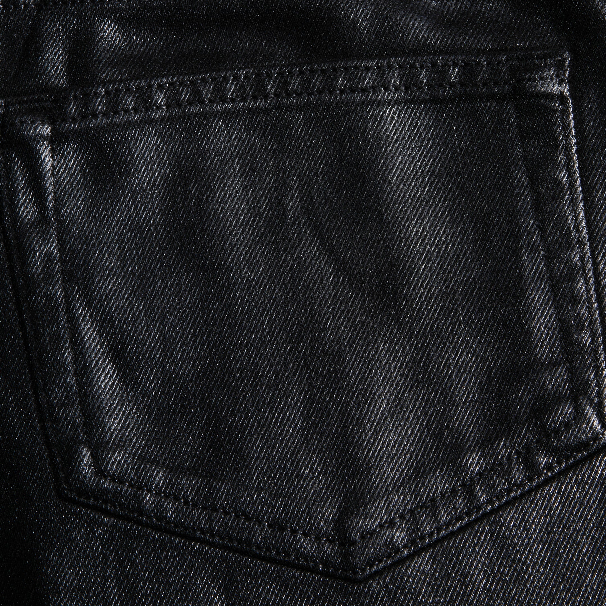 Close-up of the Mallis Coated Bow-Leg Jean pocket, highlighting the black coated denim texture and detailed stitching.