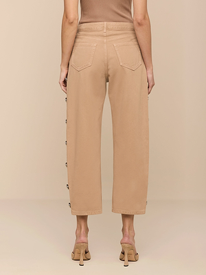 Someone wearing the Mallis Studded Bow-Leg Jean in beige with beige heeled sandals, viewed from the back against a plain beige background.