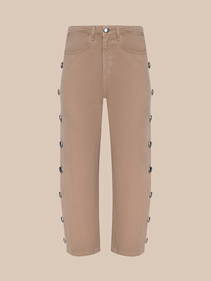 The Mallis Studded Bow-Leg Jean features a tan color, straight leg cut, black side buttons, and classic high-rise style. With front and back pockets, these jeans are shown against a beige background.