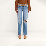 A person wearing a brown long-sleeve top, tan pointed-toe heels, and the Armida Low-Rise Slouch Jean in a vintage indigo wash with a belt, standing against a plain white background.