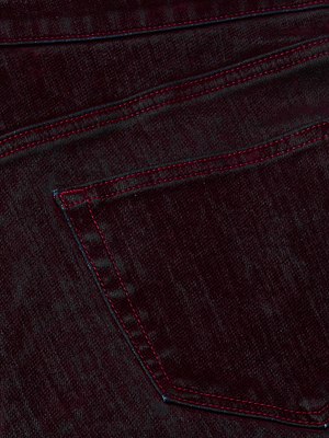 Close-up of L'AGENCE Dolores Flocked Bow-Leg Jean in dark blue denim, highlighting the back pocket's red stitching and the visible texture of its low-rise style.