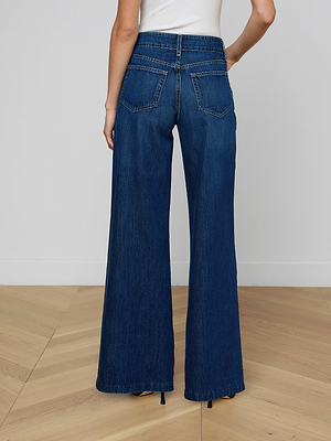 A person shown from the back wears a white sleeveless top and the Pacey Wide-Leg Jean in all-cotton denim, standing on a light wooden floor against a plain light-colored wall.