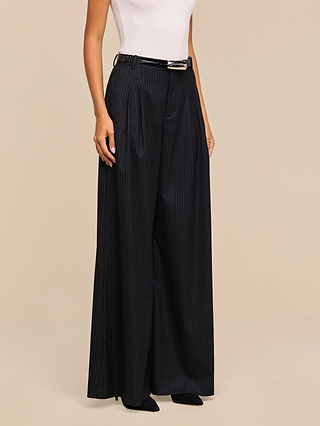 A person wearing a white sleeveless top and the Chelsy Wide-Leg Pant with a black belt, standing against a neutral background.