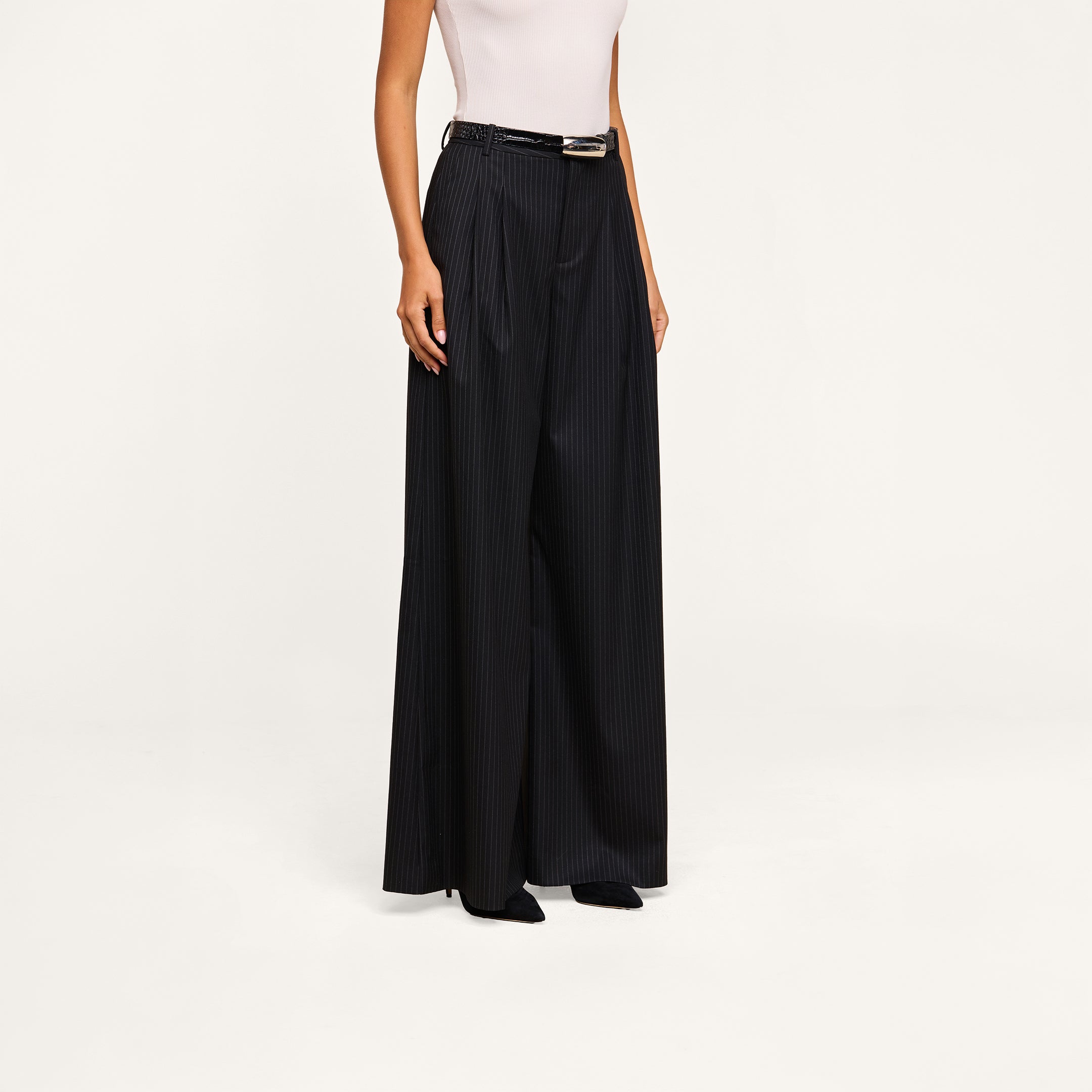 A person wearing a white sleeveless top and the Chelsy Wide-Leg Pant with a black belt, standing against a neutral background.