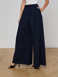 A person is wearing the Chelsy Wide-Leg Pant, made from stretch suit fabric, paired with black open-toe heels. The person is shown from the shoulders down against a plain, light background.