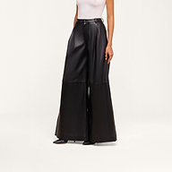 Wearing a sleeveless white top, the person pairs it with the Chelsy Leather Wide-Leg Pant and black pointed shoes, standing against a plain white background.