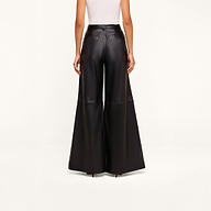 A person is wearing a white sleeveless top and high-rise, black Chelsy Leather Wide-Leg Pants made from lambskin, standing facing away against a plain light background.