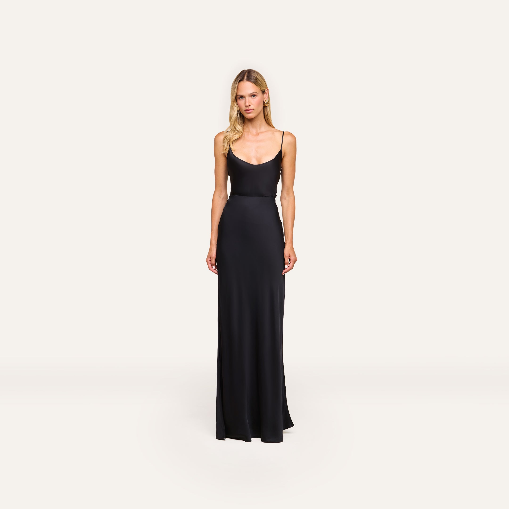 A woman with long blonde hair and a neutral expression stands against a plain background wearing the Zeta Satin Maxi Skirt.