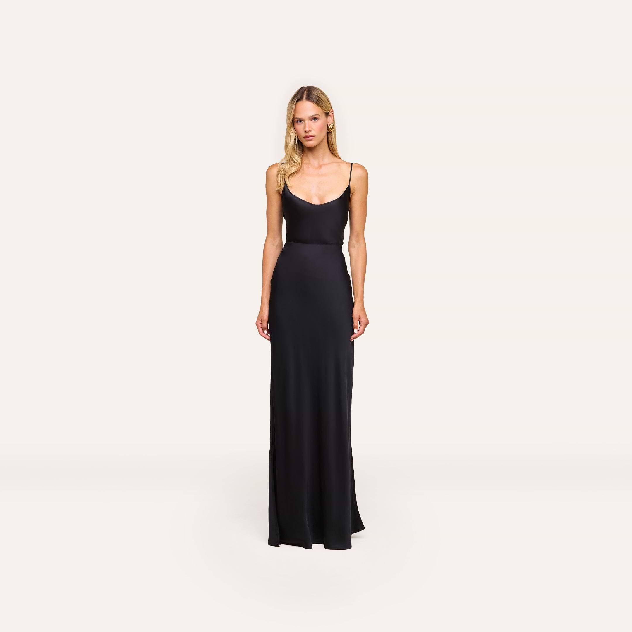 A woman with long blonde hair and a neutral expression stands against a plain background wearing the Zeta Satin Maxi Skirt.