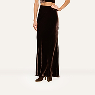 A person models the Zeta Velvet Maxi Skirt with brown boots and a cropped top, standing against a plain white background. The image focuses on the lower half of the body, highlighting a minimalist wardrobe style.