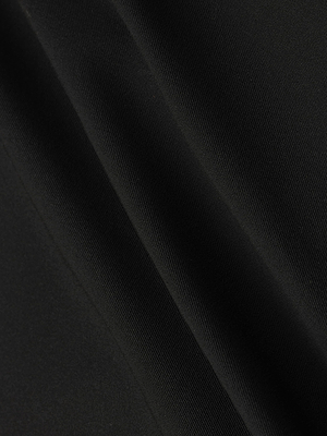 Close-up of black stretch fabric on the L'AGENCE Olyvia Pencil Skirt, showing soft texture and diagonal folds. Lighting highlights the smooth, curve-skimming fit that defines this signature skirt.