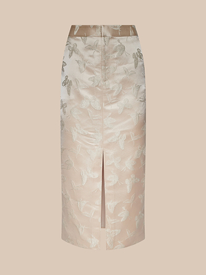 La gonna Madonna Midi è a vita alta, lunga fino al ginocchio, in raso jacquard beige chiaro con motivo a farfalla lucida e spacco centrale anteriore, su fondo beige tinta unita.