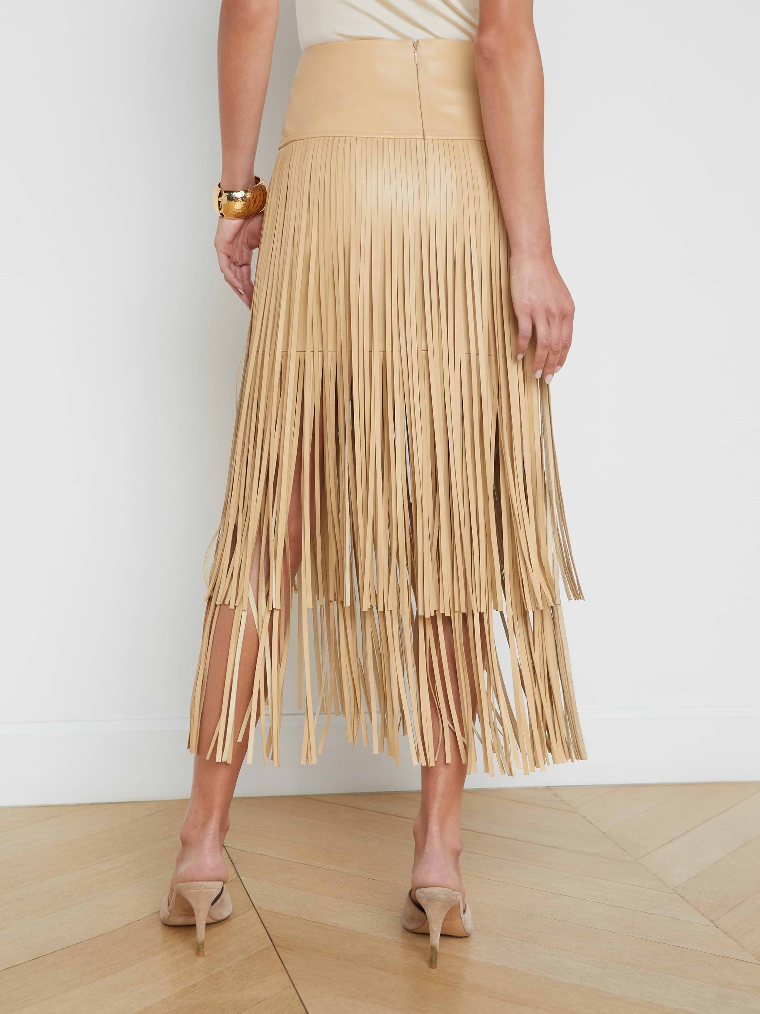 A person wearing the Karolina Fringe Skirt and high-heeled shoes is standing with their back toward the camera against a plain white background.
