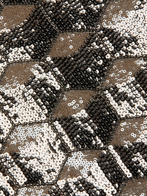 Close-up of the Leroy Sequin Mini Skirt by L'AGENCE, featuring shiny black, white, and silver hexagonal sequins in a geometric pattern for a reflective, textured look—perfect for a night out.