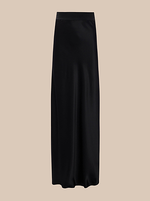 La jupe longue Ryker Silk est une jupe noire au tombé fluide et à la finition légèrement brillante, présentée ici sur un fond beige.