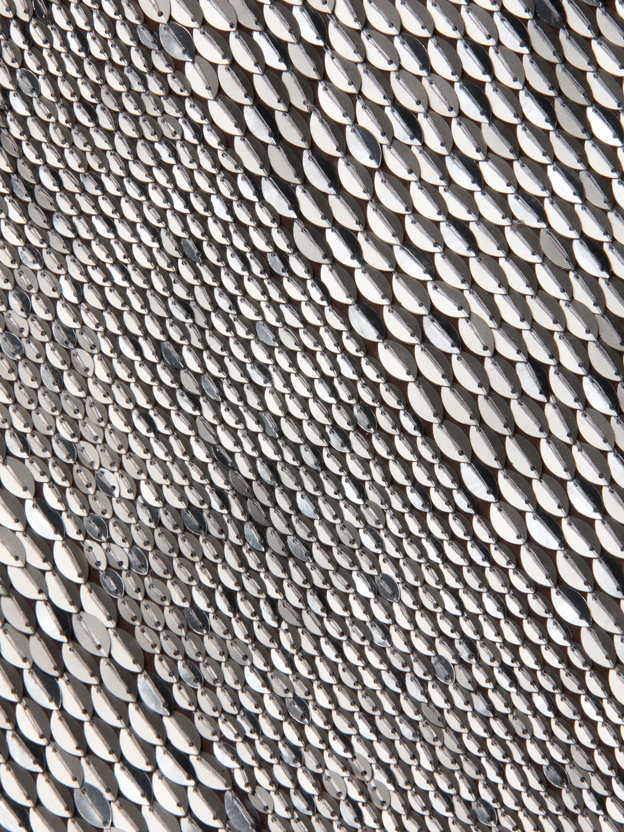 Close-up of the Dion Sequin Mini Skirt’s textured surface, covered in small, shiny silver sequins arranged in overlapping rows that create a reflective, wavy pattern reminiscent of hand-embroidery.