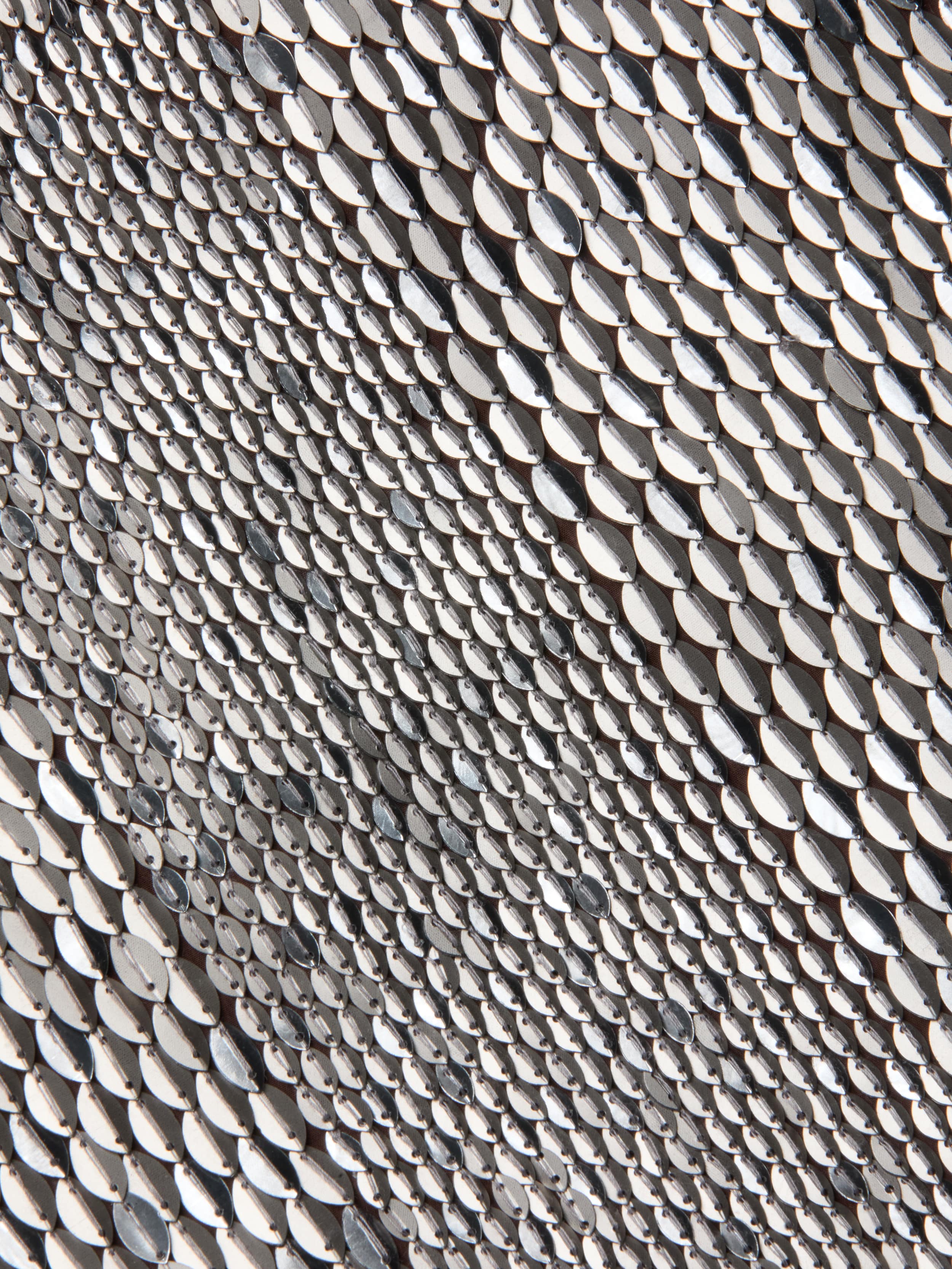 Close-up of the Dion Sequin Mini Skirt’s textured surface, covered in small, shiny silver sequins arranged in overlapping rows that create a reflective, wavy pattern reminiscent of hand-embroidery.