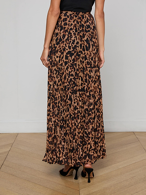A person wears the L'AGENCE Torin Pleated Maxi Skirt in brown and black leopard print poly chiffon, paired with black heeled shoes on a wooden floor.