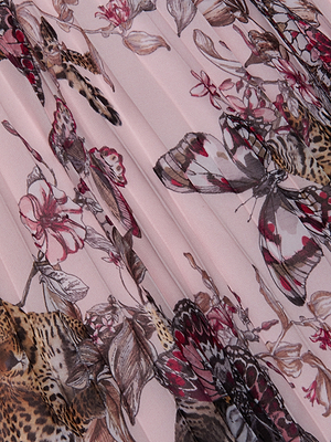 A close-up of the Torin Pleated Maxi Skirt’s poly chiffon fabric, showcasing a detailed jungle print with butterflies, leopards, pink flowers, and green leaves on a pink background.