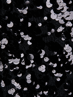 Close-up of the Makena Sequin Pencil Skirt, showcasing black and white sequins on dark textured fabric for a sparkling, reflective finish—ideal for a night out or party look.