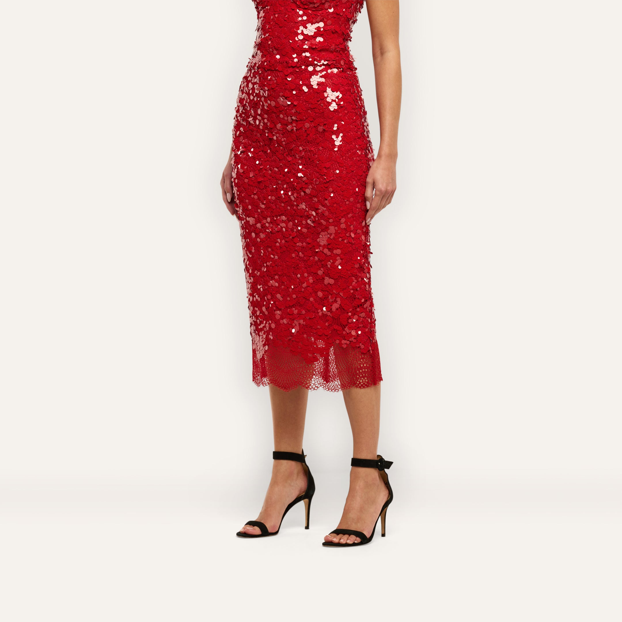A person wears a red sequined Makena Sequin Pencil Skirt that falls below the knee, paired with black high-heeled sandals.