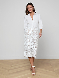 A woman wearing a white button-up blouse and the Makena Sequin Pencil Skirt stands against a plain light background, posing with one foot forward. She completes the look with white heeled sandals, embracing fresh spring fashion.