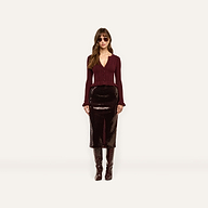 A model wears a long, espresso brown Makena Sequin Pencil Skirt, a burgundy button-down top with ruffled cuffs, and knee-high boots.
