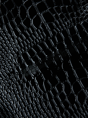 Close-up of the Gerard Croc-Embossed Mini Skirt by L'AGENCE, featuring shiny black vegan leather with raised, irregular croc-like scales that catch the light.