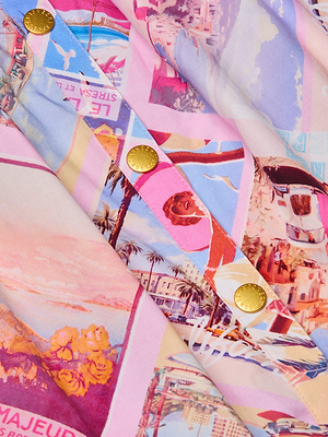 Close-up of the Seina Poplin Midi Skirt, adorned with colorful vintage-style travel illustrations in pink, purple, blue, and yellow, and finished with gold Versace-logo embossed buttons.