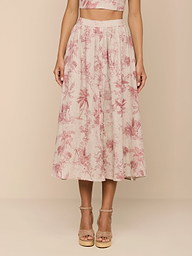 A person wears the Seina Linen Midi Skirt with a pink jungle toile print and tan platform sandals; only their lower torso and legs are seen against a beige background.