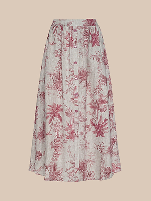 The Seina Linen Midi Skirt is a high-waisted, button-down midi skirt with a white base and red jungle toile print of palm trees and foliage, displayed on a pale peach backdrop.
