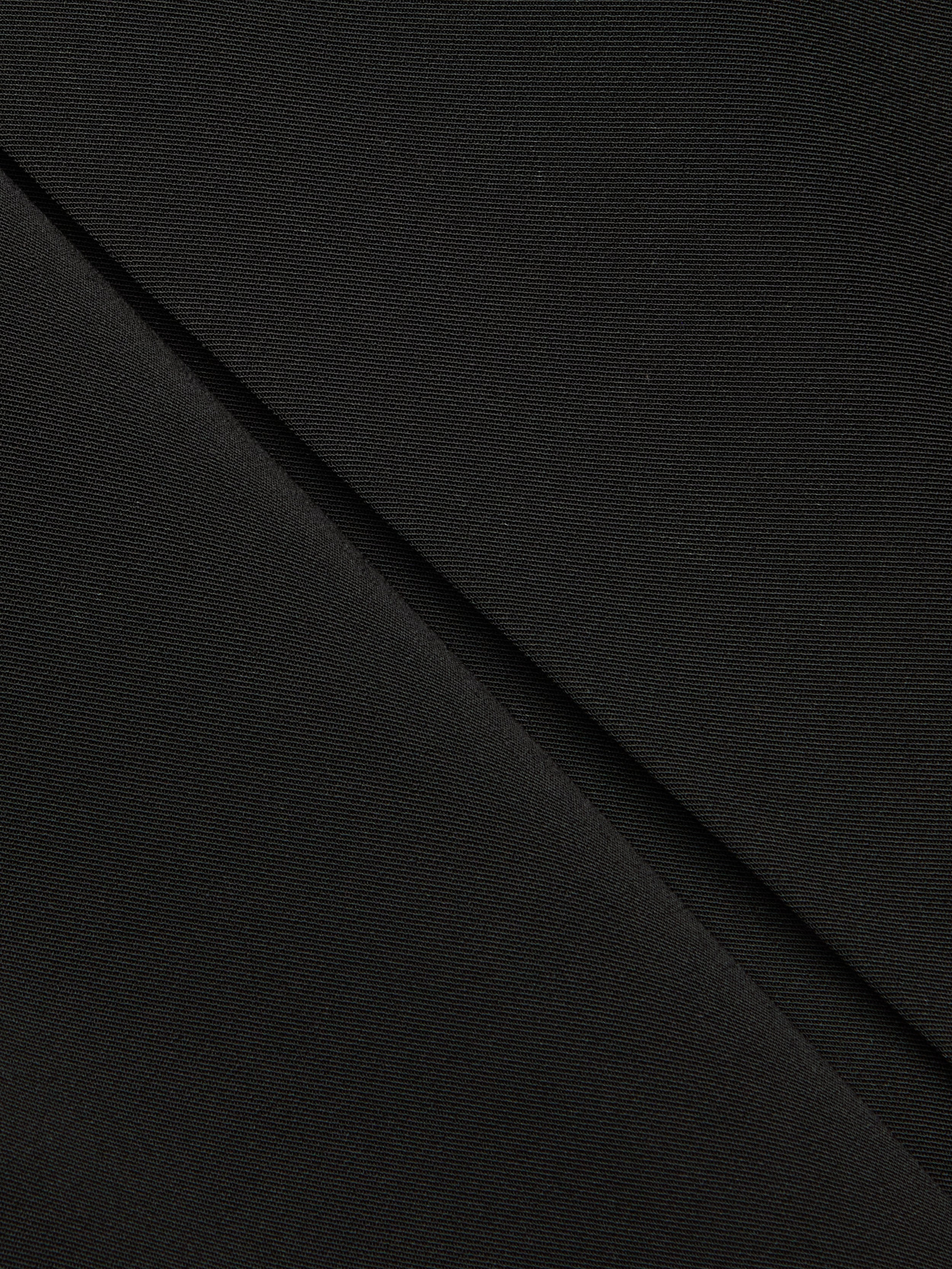 Close-up of black fabric with a diagonal fold, showing fine texture and subtle weave pattern—ideal for the Tania Pleated Mini Skirt.