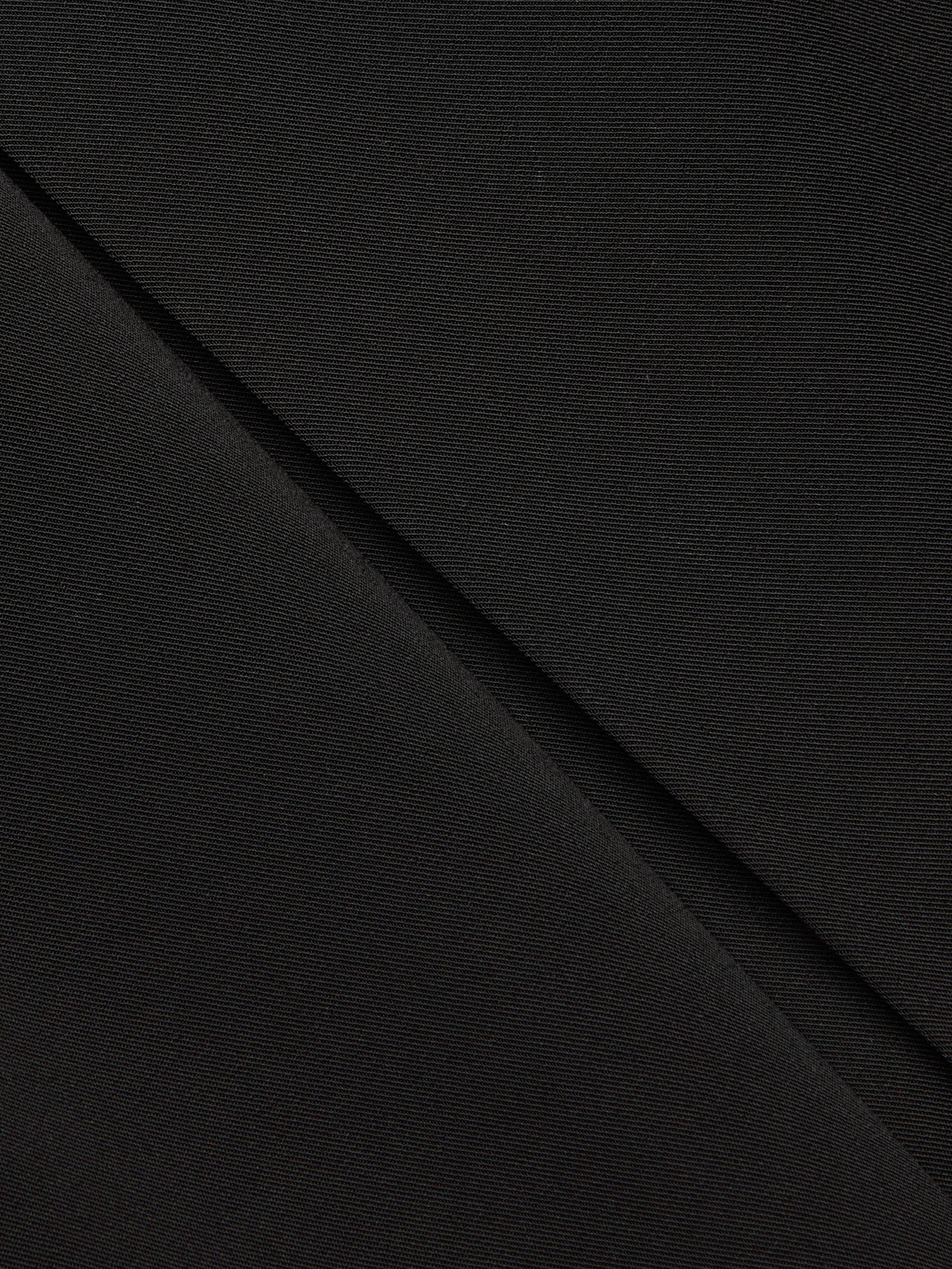 Close-up of black fabric with a diagonal fold, showing fine texture and subtle weave pattern—ideal for the Tania Pleated Mini Skirt.