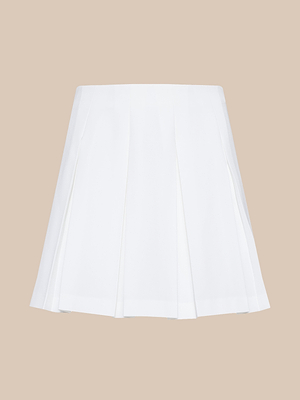 The Tania Pleated Mini Skirt, a modern prep white mini skirt, is displayed against a plain beige background.