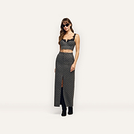 A person wears a cropped corset top with lace trim and a matching velvet polka dot Maceline Maxi Skirt featuring a front slit, paired with black sunglasses and knee-high boots.
