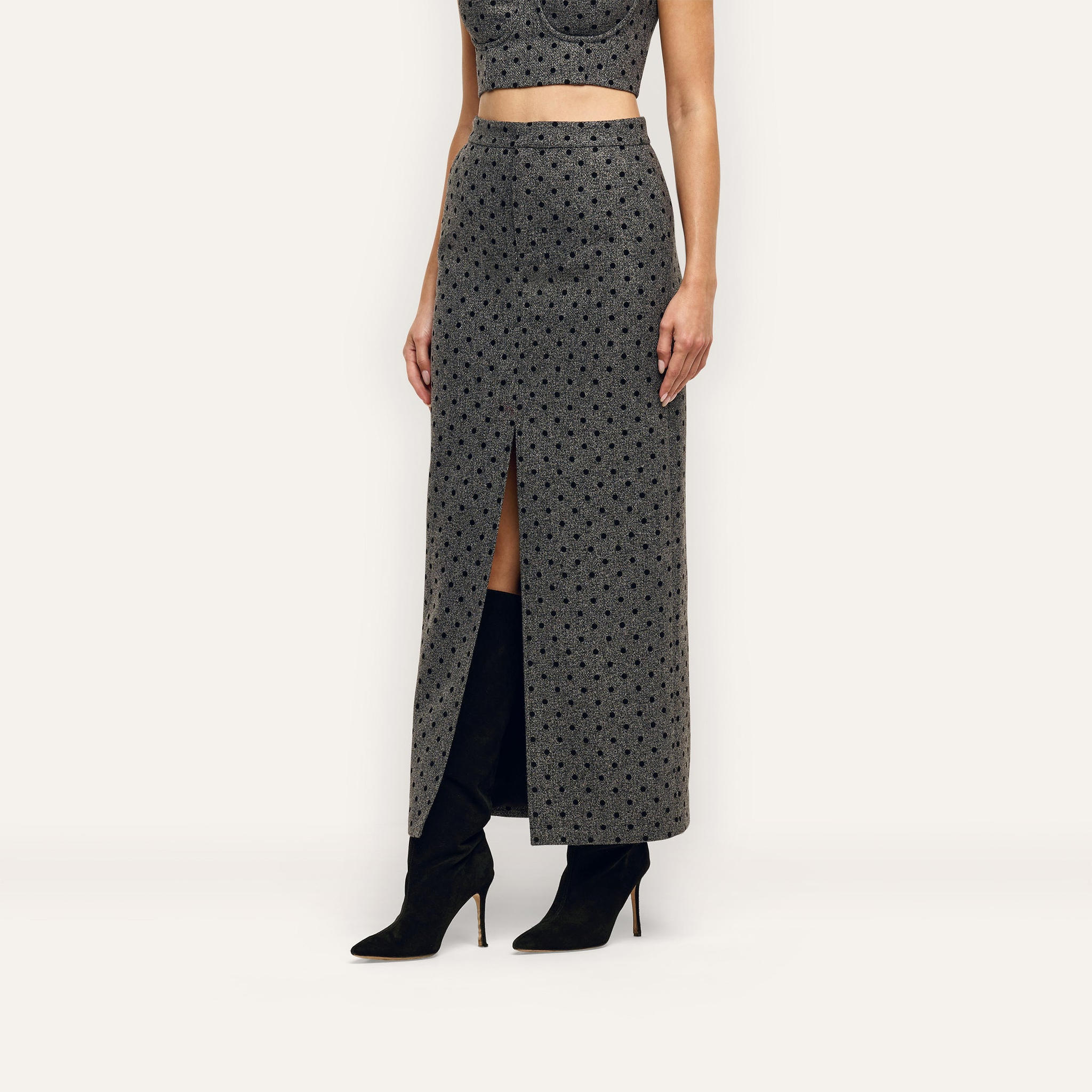 Maceline Maxi Skirt, a grey pencil skirt featuring a black velvet polka dot pattern and a front center slit, worn with black knee-high boots.