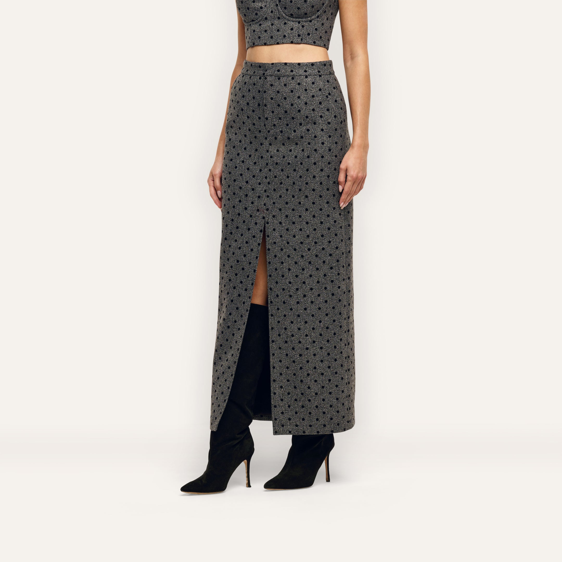 Maceline Maxi Skirt, a grey pencil skirt featuring a black velvet polka dot pattern and a front center slit, worn with black knee-high boots.
