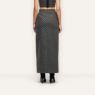 A person viewed from behind, wearing a grey polka-dot Maceline Maxi Skirt and black heeled boots.
