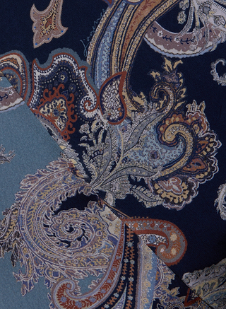 Close-up of overlapping fabrics with intricate paisley print patterns in midnight blue, navy, beige, and orange tones, creating a rich, detailed, and colorful textile design reminiscent of the Patrica Maxi Skirt.