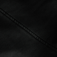 Close-up of the Robyn Vegan Leather Skirt in black, showcasing its smooth, slightly pebbled texture. A diagonal seam runs across the surface, emphasizing the material’s grain and the neat stitching along the seam.