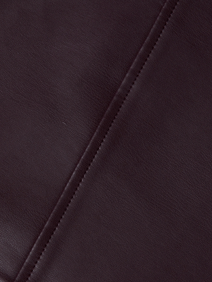 Close-up of dark brown vegan leather with visible grain and a stitched seam, showcasing the fine craftsmanship of the L'AGENCE Robyn Vegan Leather Midi Skirt.