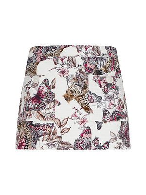 The Cyra Low-Rise Mini Skirt is a white mini skirt with a bold butterfly, leopard, and leaf print, finished with two gold front buttons.