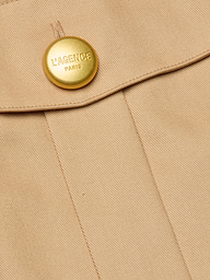 Close-up of the Maelis Mini Skirt in beige, featuring a gold button engraved with LAGENCE PARIS near the seam and flap, highlighting the tailored detail of this high-rise waist design.