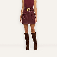 Maelis Vegan Leather Skirt in burgundy, featuring a paperbag mini silhouette, buckled waist belt, two front cargo pockets, and gold hardware.