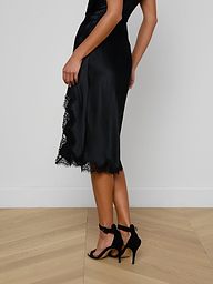 A person wearing the Tico Silk Lace Skirt and black high-heeled sandals stands against a plain light background.
